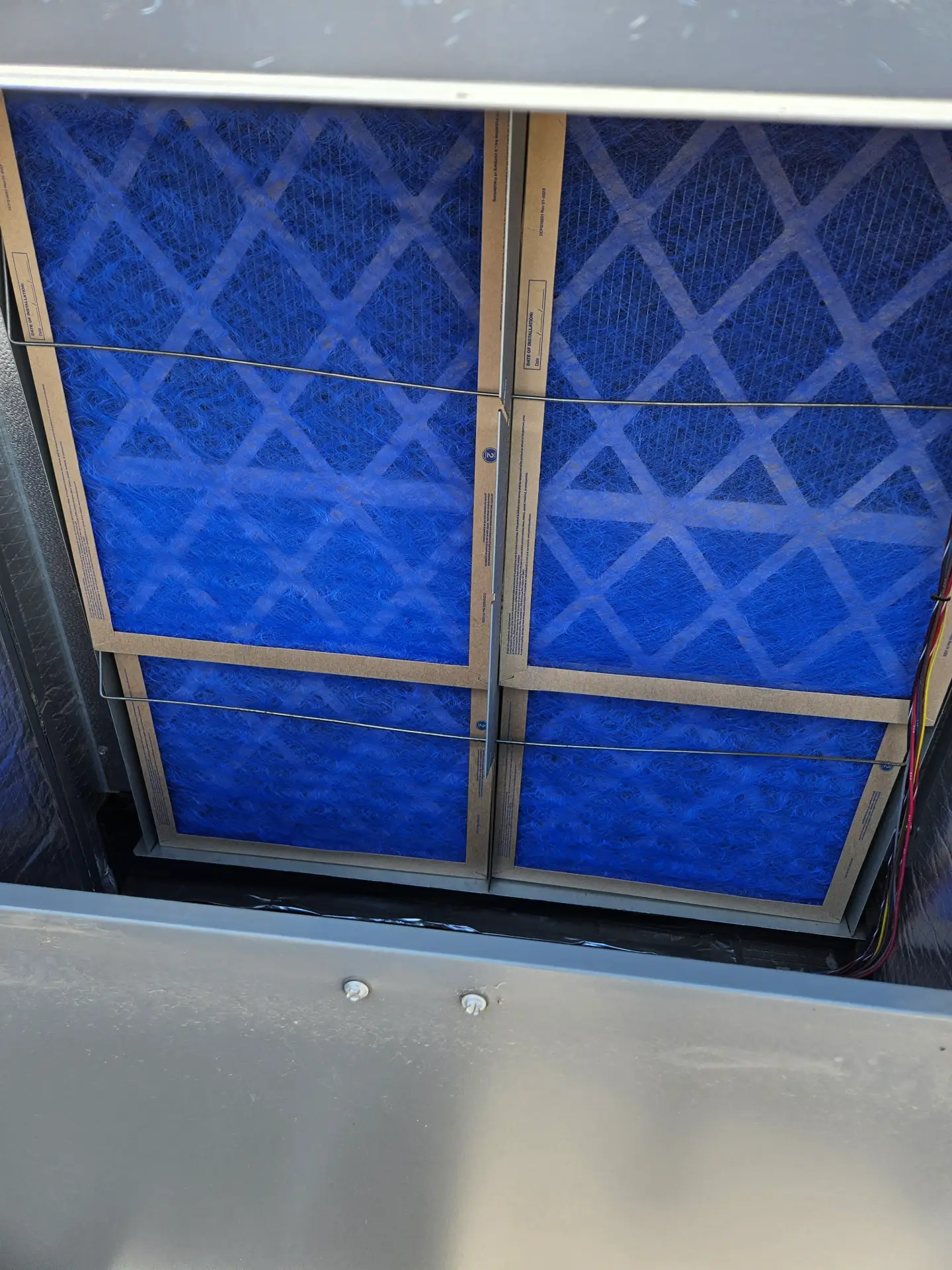 Blue pleated HVAC air filter being replaced